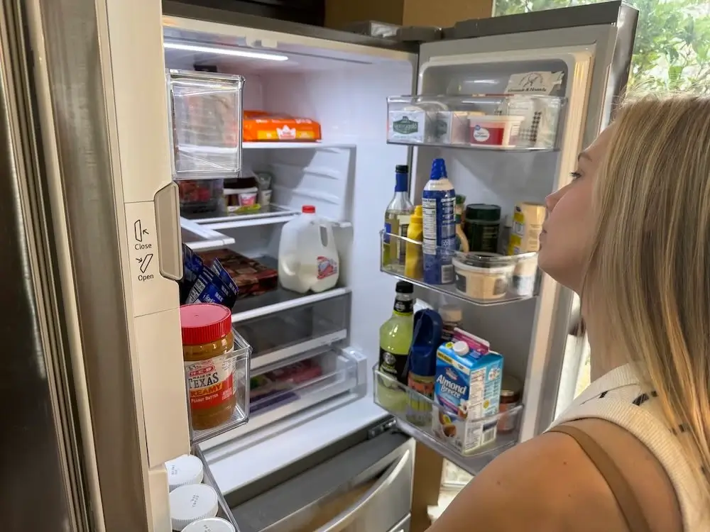 Image showing a person opening their fridge, because sleep deprivation increases the hunger hormone (ghrelin).