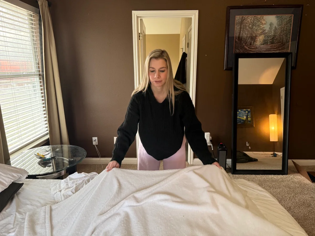 An image illustrating a woman preparing bedding to be washed.