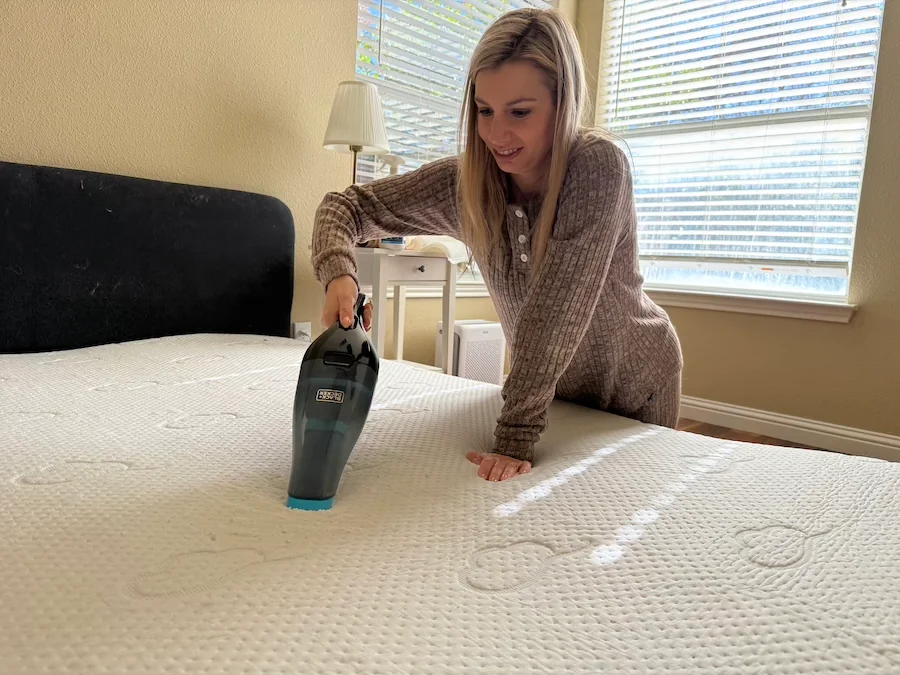 An image illustrating a woman vacuuming up baking soda on a stained mattress,