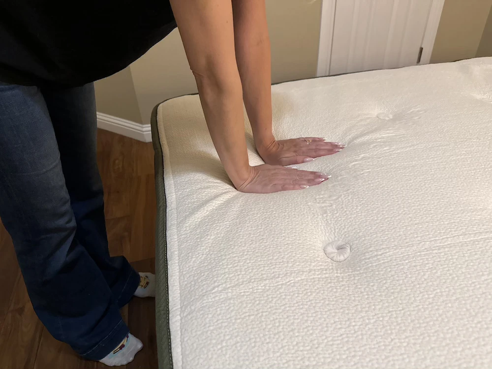 Hands pressing into the responsive surface of the Avocado Green mattress