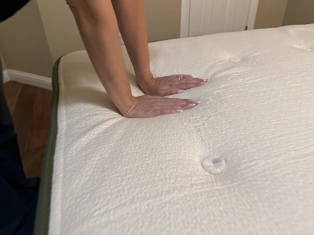 Hands pressing into the tufted surface of the Avocado Green mattress