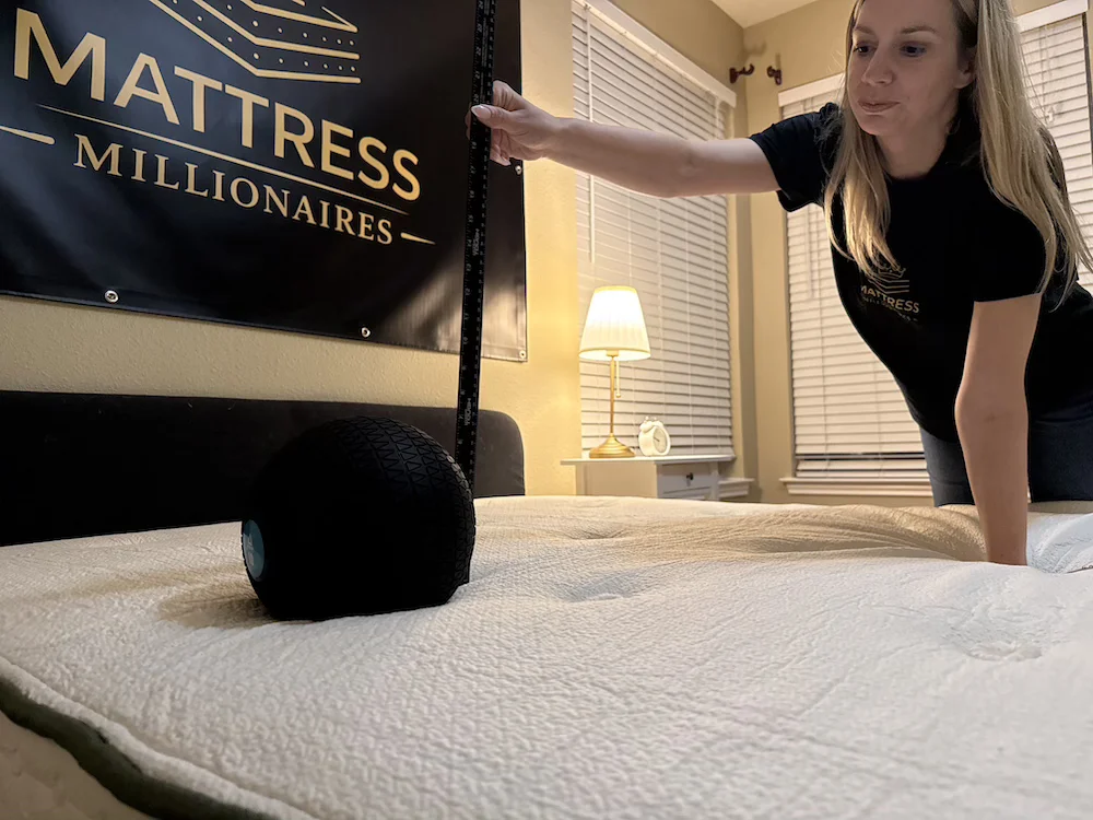 Measuring sinkage on the Avocado Green mattress with a weighted ball and ruler