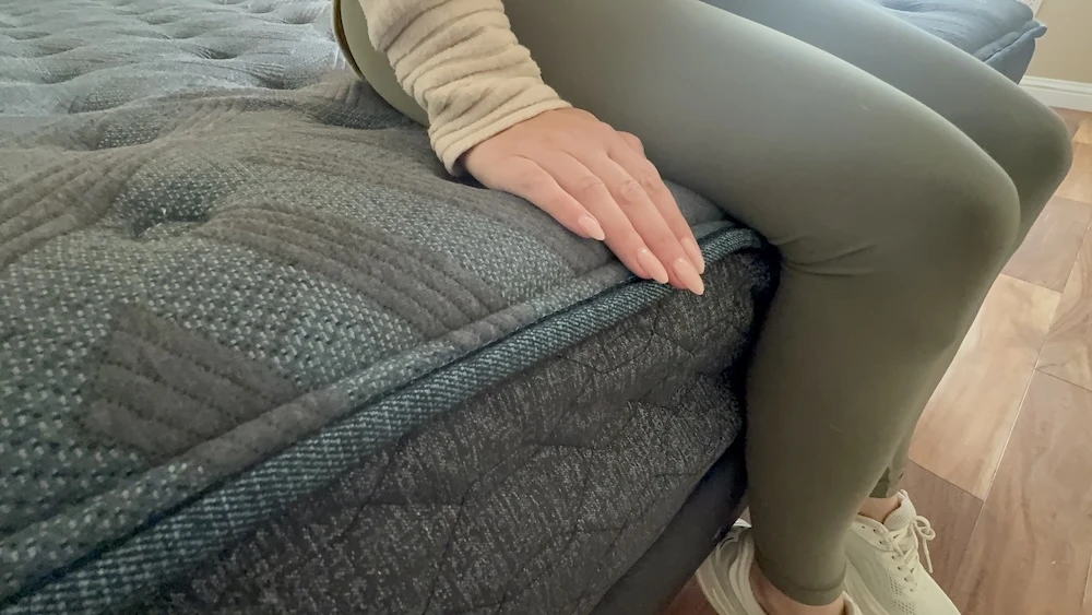 Tester sitting on the edge of the Beautyrest Level One mattress