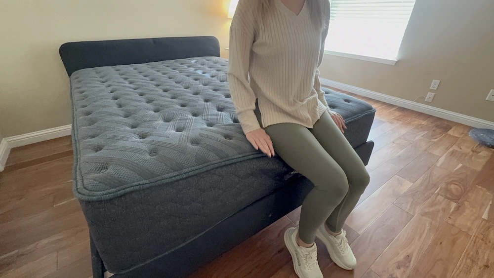 Tester sitting on the edge of the Beautyrest Level One Medium mattress