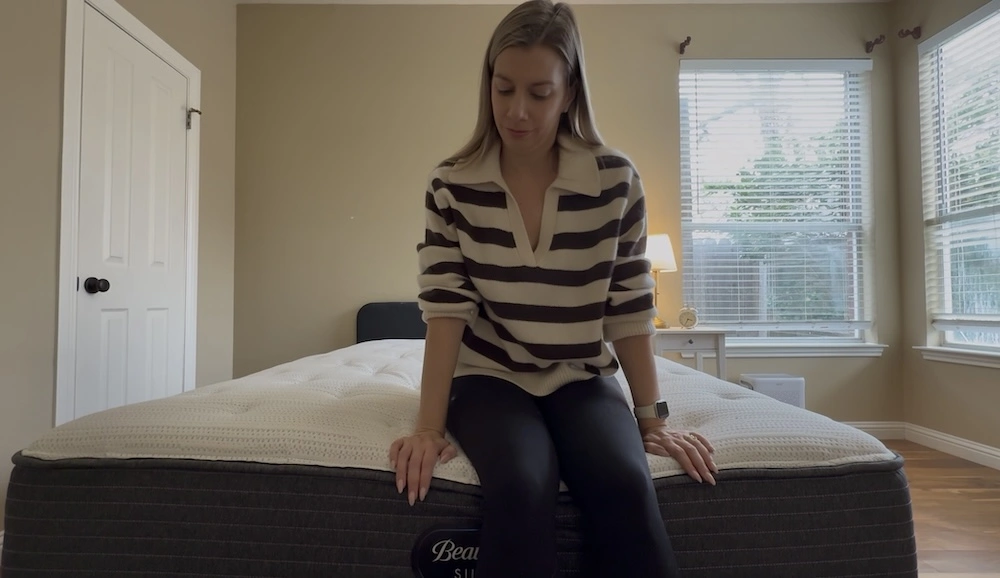 Woman sitting on the edge of the Beautyrest Silver BRS900 mattress