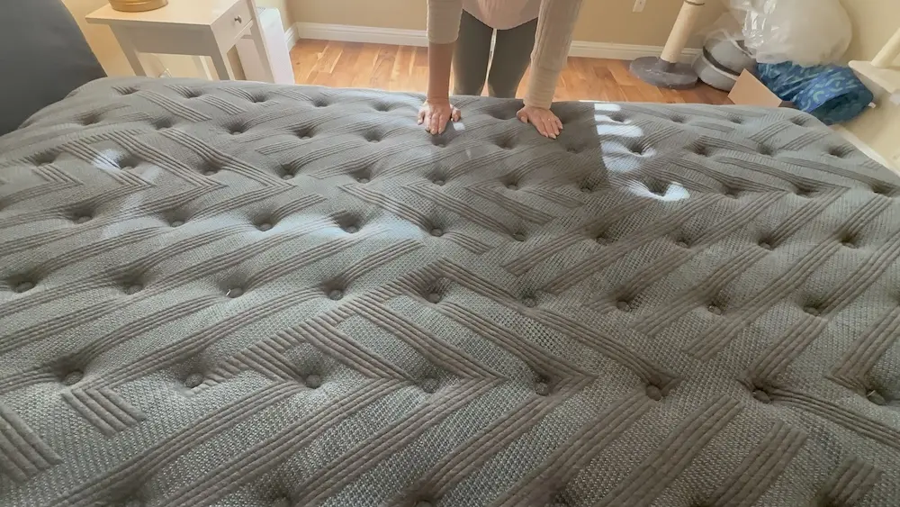Hands pressing into the quilted Beautyrest Silver BRS900 mattress surface during responsiveness testing