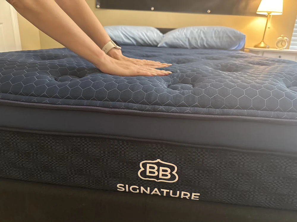 Hands pressing into Brooklyn Bedding Signature Hybrid mattress showing surface contouring and responsiveness