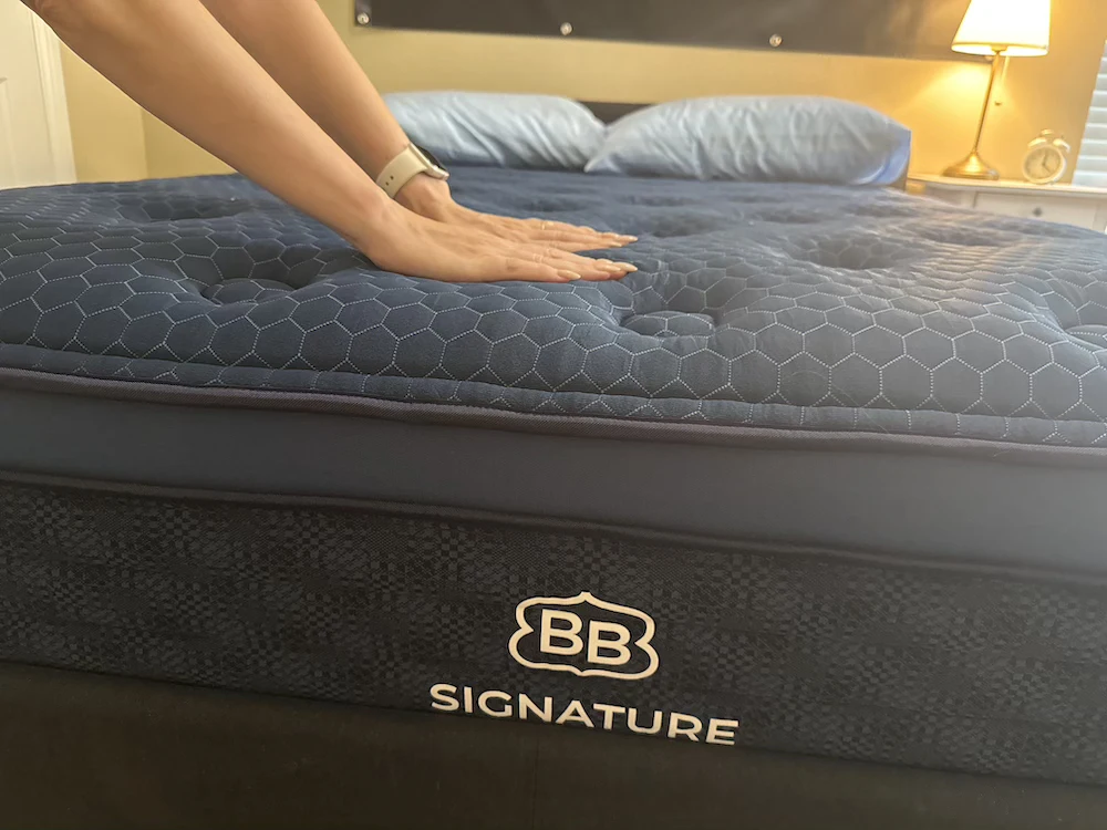 Hand pressing Brooklyn Bedding Signature Hybrid mattress showing surface firmness and responsiveness
