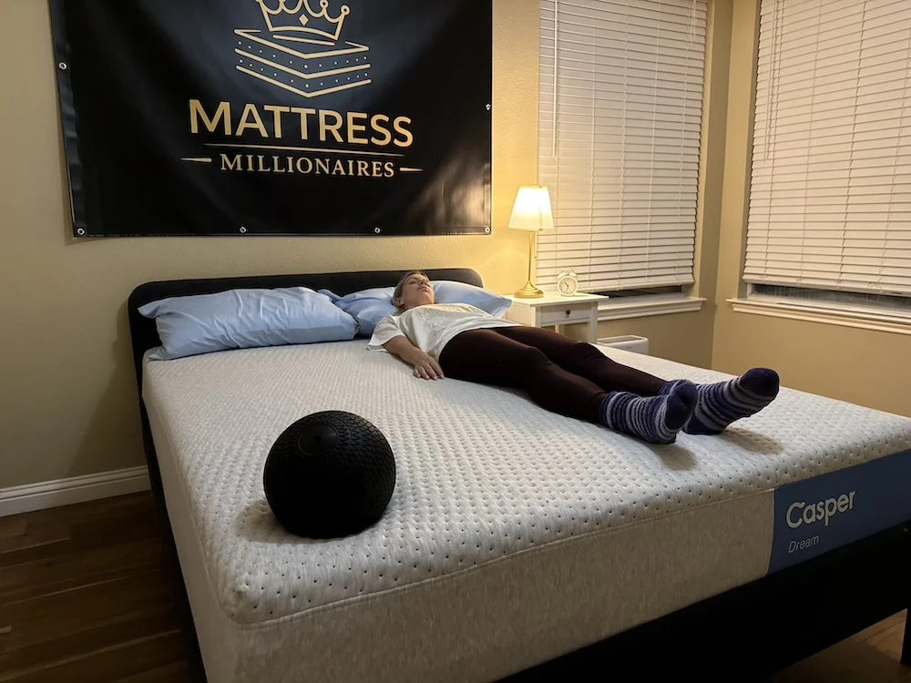 Tester lying on Casper Dream mattress in back sleeping position during firmness testing