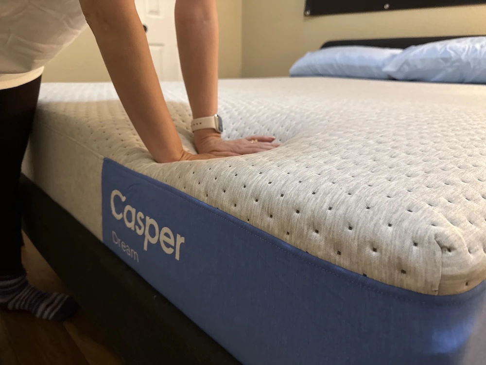 Pressing into the Casper Dream mattress to test responsiveness and foam recovery