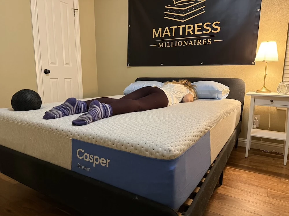 Tester lying on Casper Dream mattress in stomach sleeping position during support testing