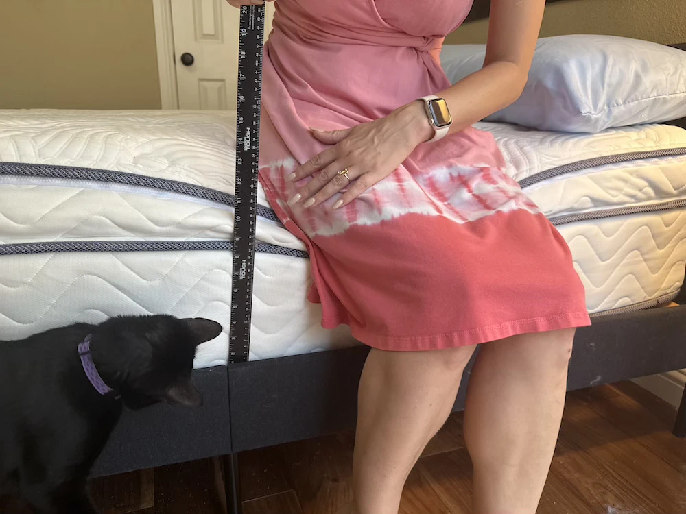 Tester measuring DLX Premier Hybrid edge support while sitting on the mattress