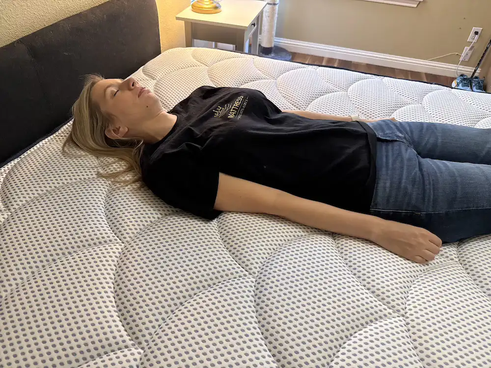 Mattress Millionaires tester evaluating pressure relief on DreamCloud Premier Hybrid mattress