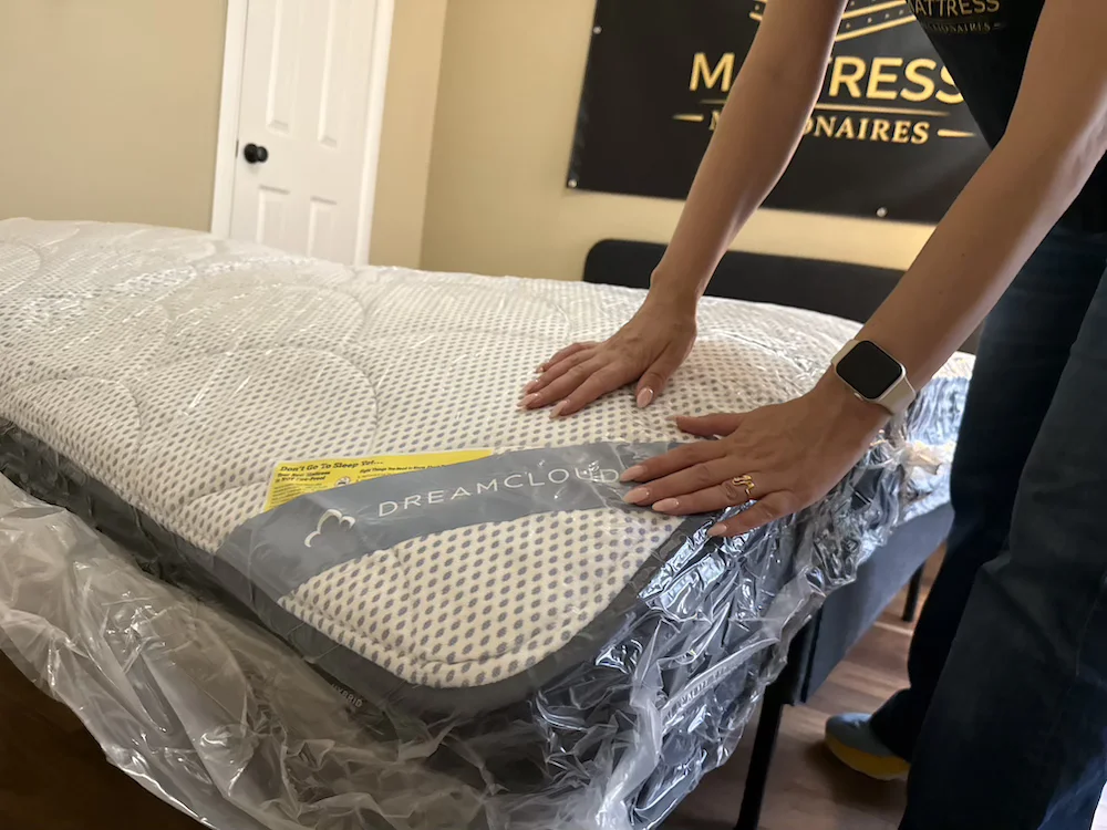 Pressing on the surface of the DreamCloud Premier mattress to test feel