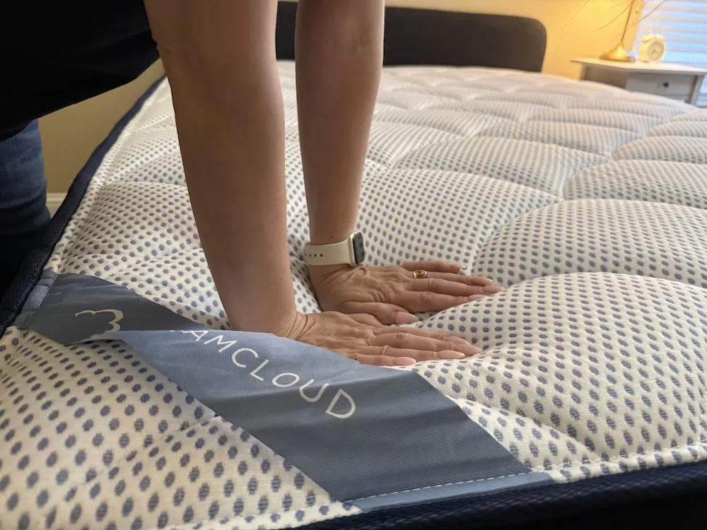 Hands pressing the DreamCloud Premier foam comfort layers