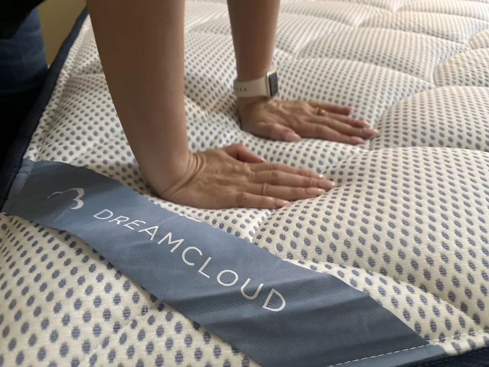 Hands pressing into the DreamCloud Premier pillow-top surface to show plush cushioning