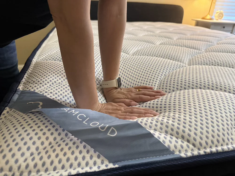 Hands pressing into the DreamCloud Premier mattress during pressure relief testing