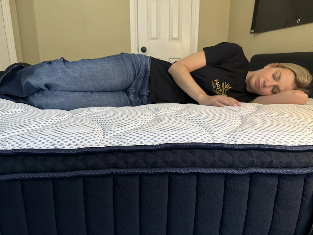 Tester side sleeping on DreamCloud Premier mattress showing pressure relief at shoulders and hips