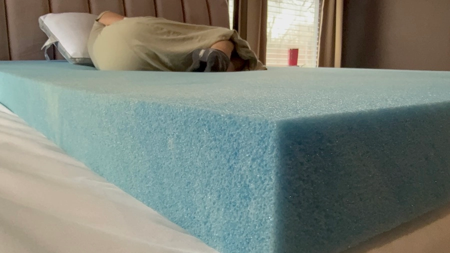 An image of a woman, sleeping on a pillow and a memory foam bed.