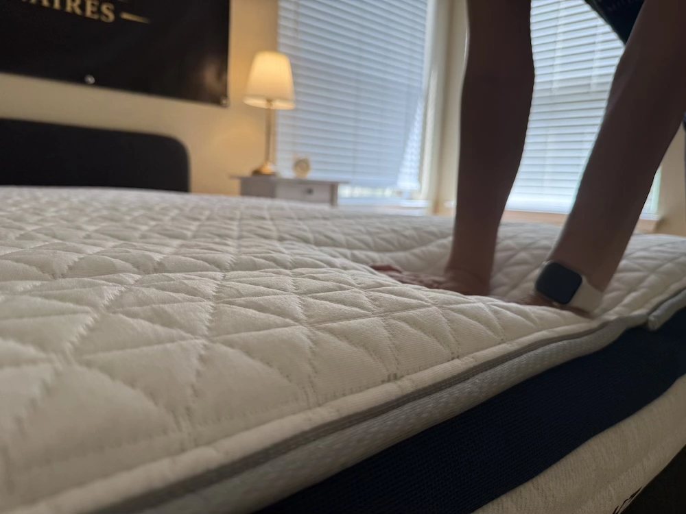 Hands pressing into the Helix Midnight mattress surface to test cushioning and response