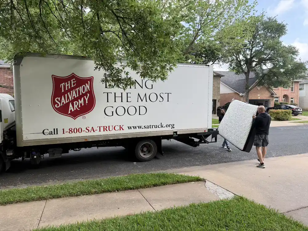 Salvation Army donation truck collecting a used mattress from a residential neighborhood