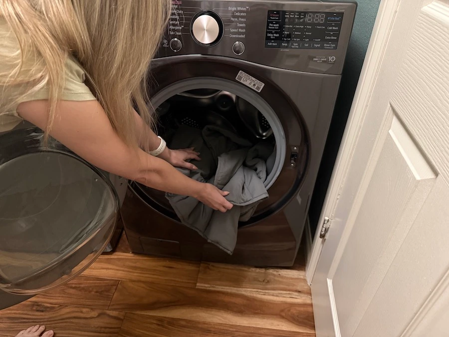 Image of a woman putting a weighted blanket in the washing machine.