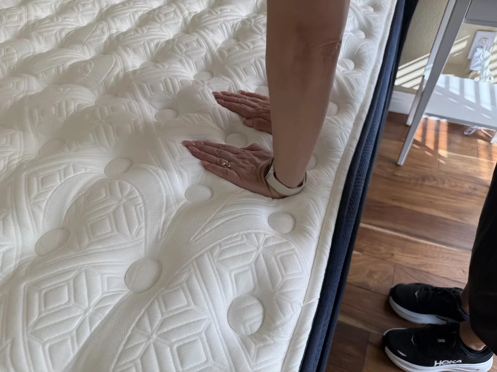 Hands pressing into the quilted Kirkland Lakeridge Pillow Top to test surface compression