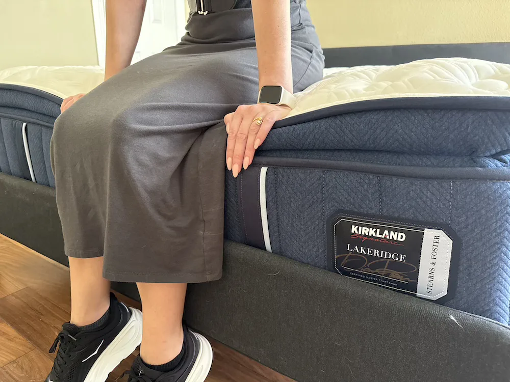 Tester sitting on the edge of the Kirkland Lakeridge mattress during edge support testing