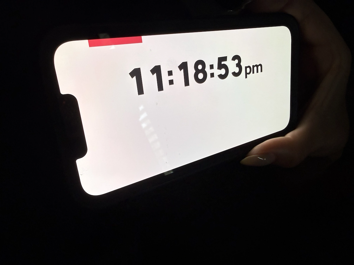 Smartphone displaying a late-night time on a bright screen in a dark room
