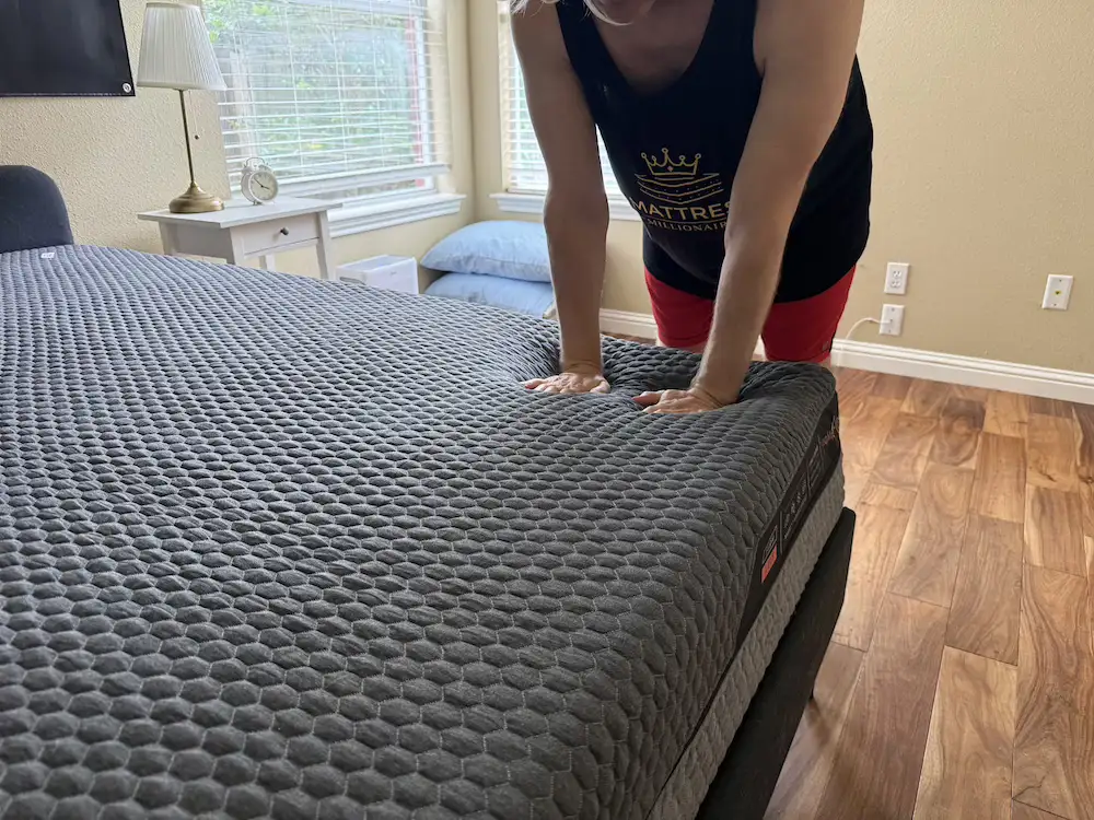 Hands pressing into the Layla Hybrid Flippable mattress during firmness testing