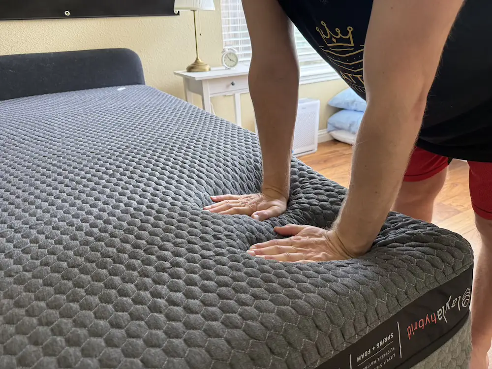 Hands pressing into the Layla Hybrid mattress during pressure relief testing