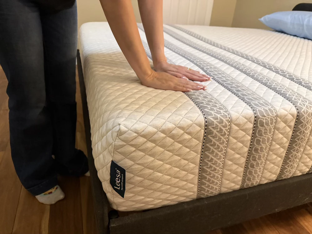 Tester pressing the Leesa Sapira Hybrid to assess its firm responsive surface feel