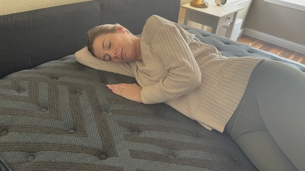 Woman sleeping on her side on a dark mattress in a bedroom