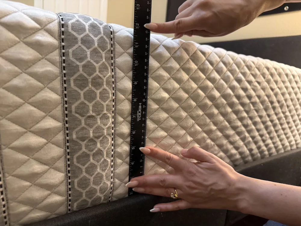 Close-up of a ruler held vertically against the quilted side of a mattress to measure its height