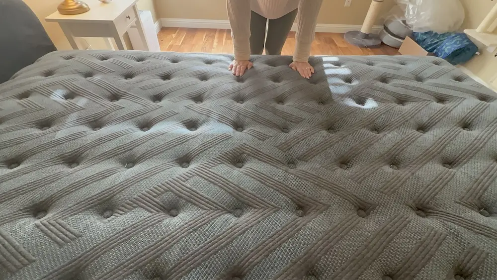 Close-up of hands pressing into mattress surface showing softness and responsiveness