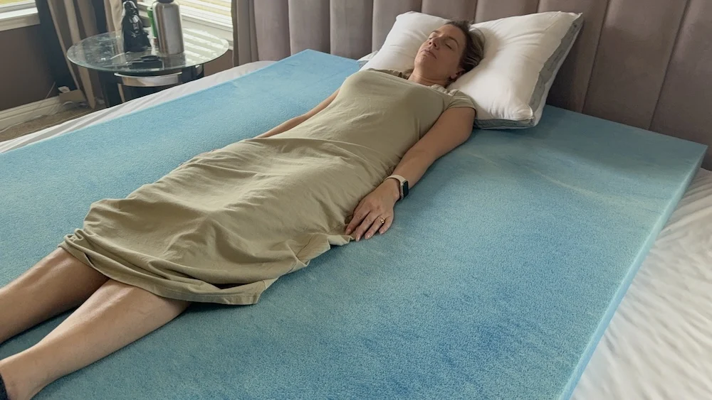 Woman lying on a blue foam topper placed on a mattress