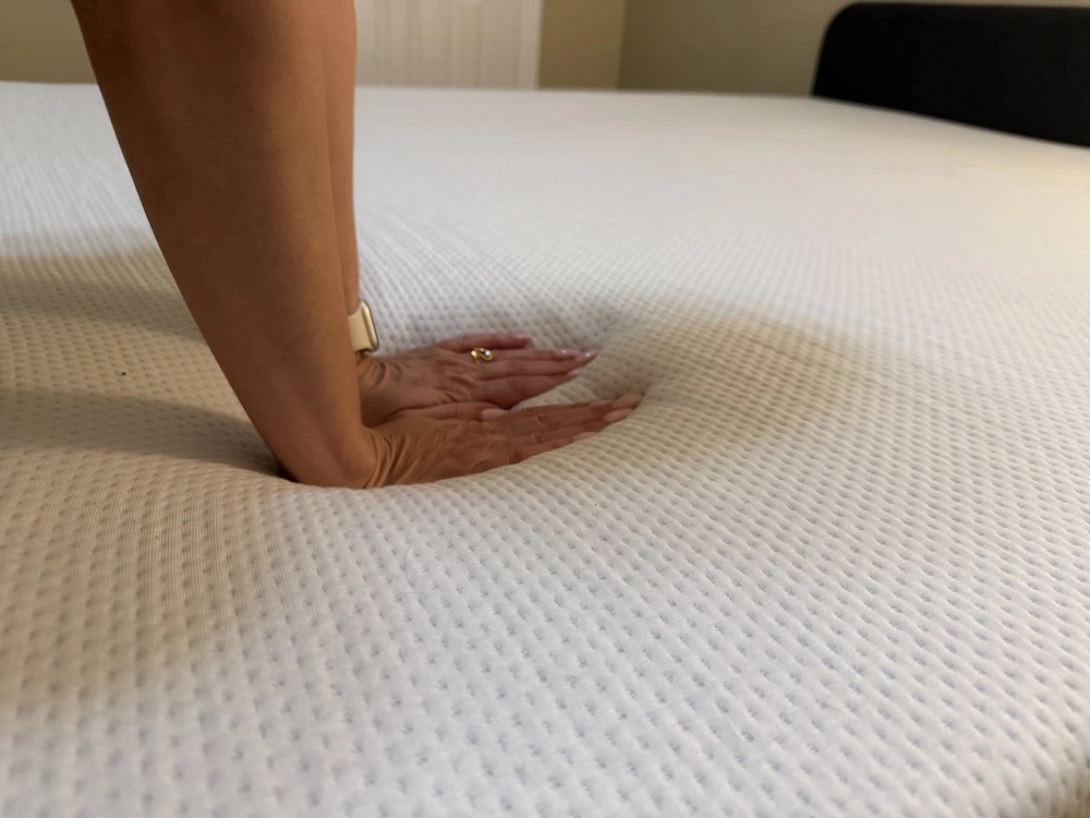Hands pressing into memory foam mattress showing deep contouring and pressure relief
