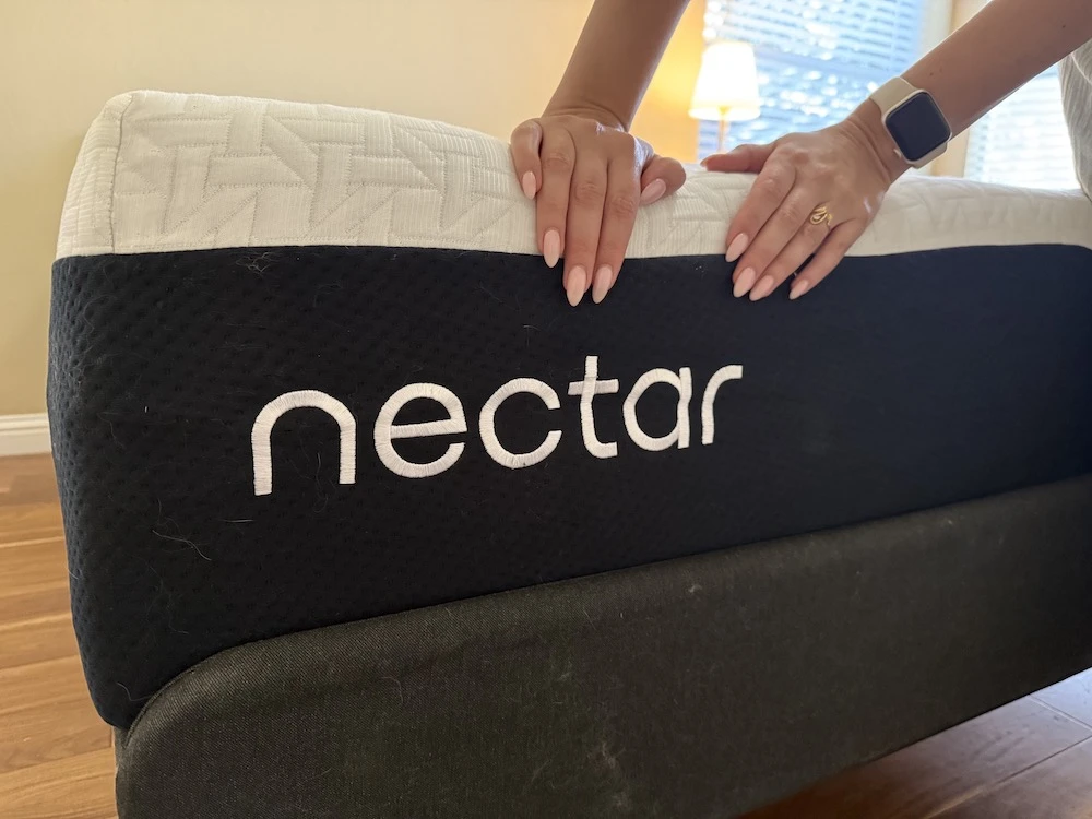 Hands pushing down on the edge of Nectar Premier mattress showing foam compression and edge support performance