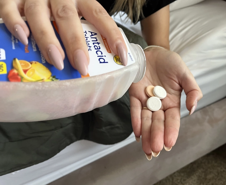 Close-up of antacid tablets being poured into a hand for relief of acid reflux symptoms.