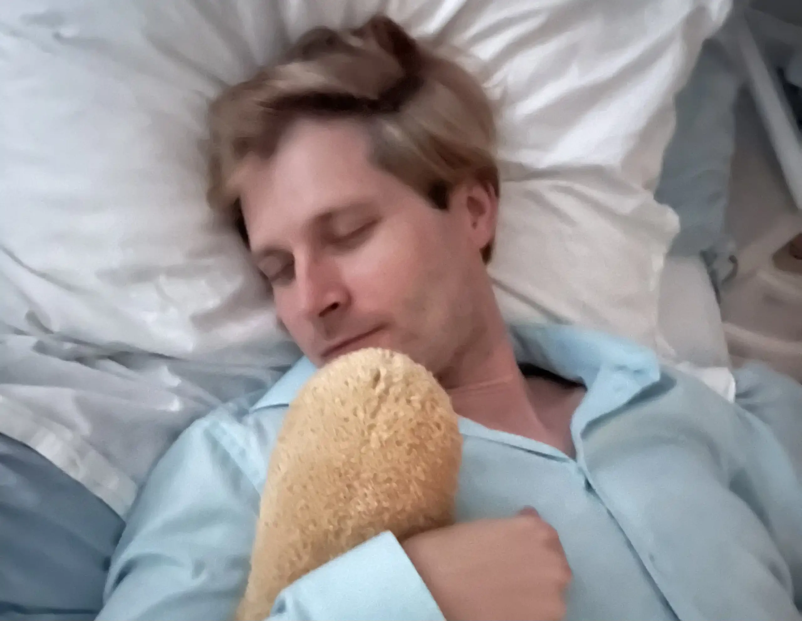 Sleeping adult man in bed to represent recommended nightly sleep for adults