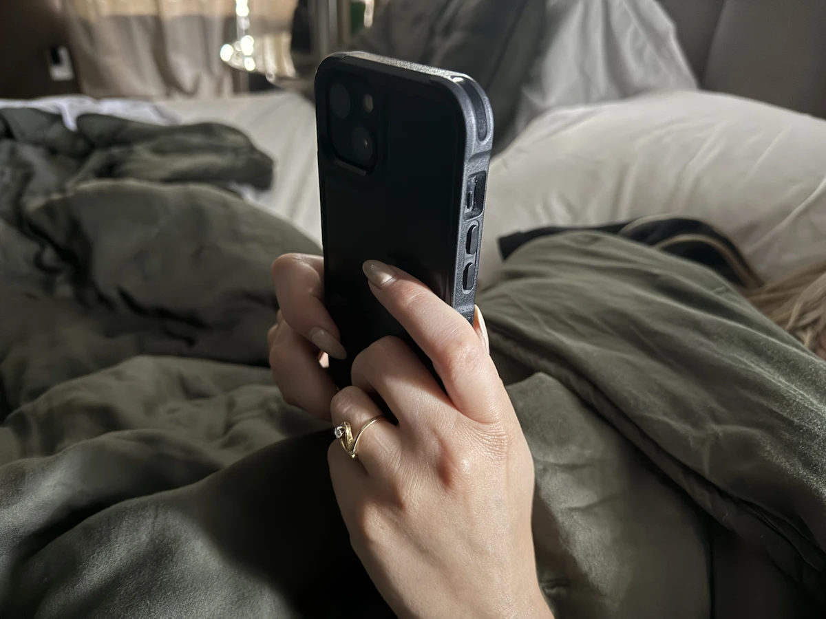 Person holding a smartphone while lying in bed before sleep