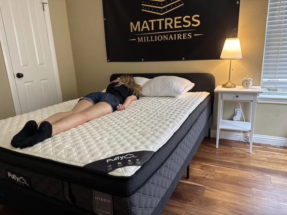 Puffy Lux Hybrid mattress full setup with tester lying face down\