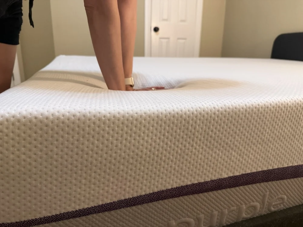 Pressing into Purple Plus mattress to test pressure relief