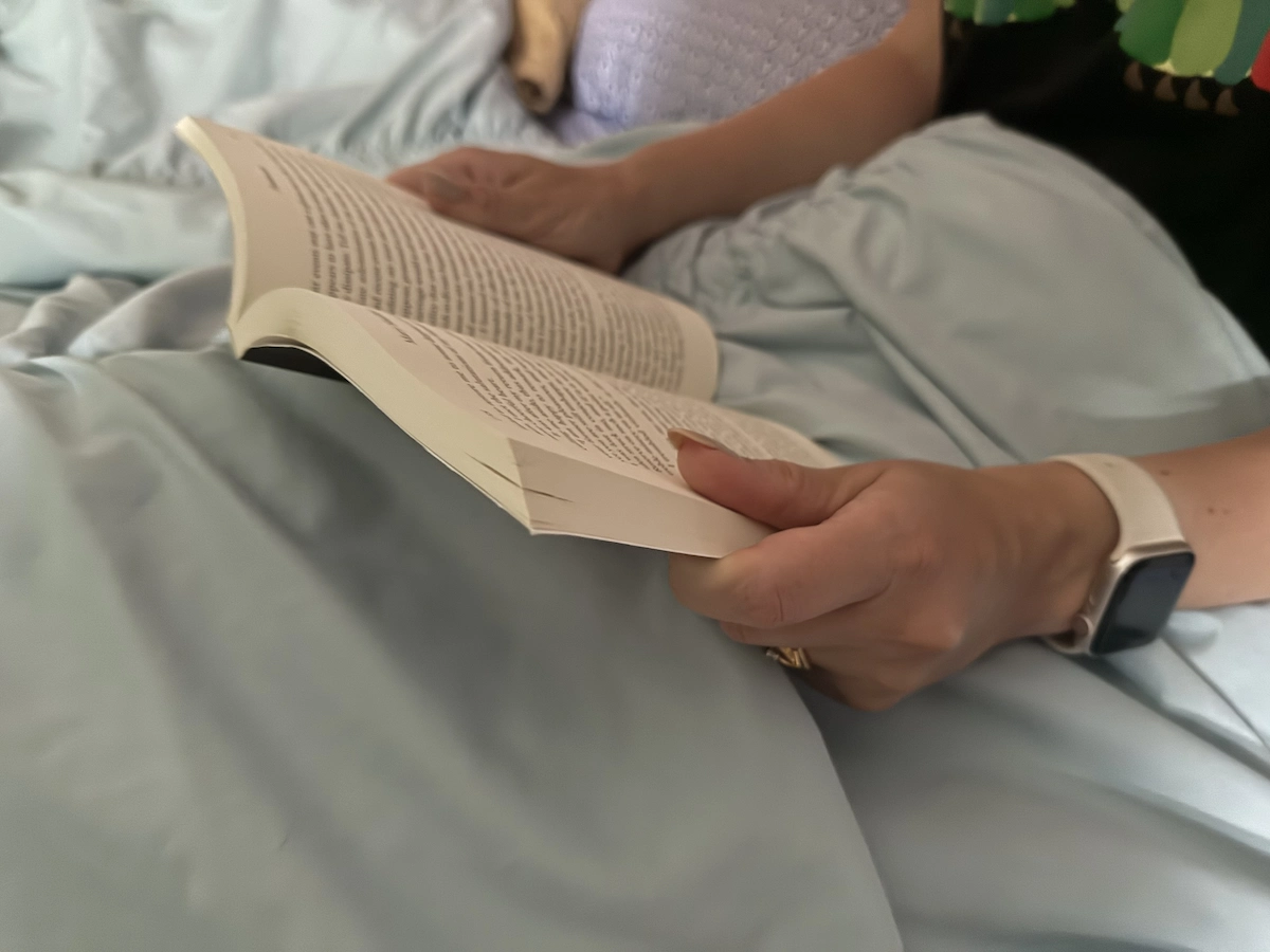 Person reading a physical book in bed as part of a bedtime routine