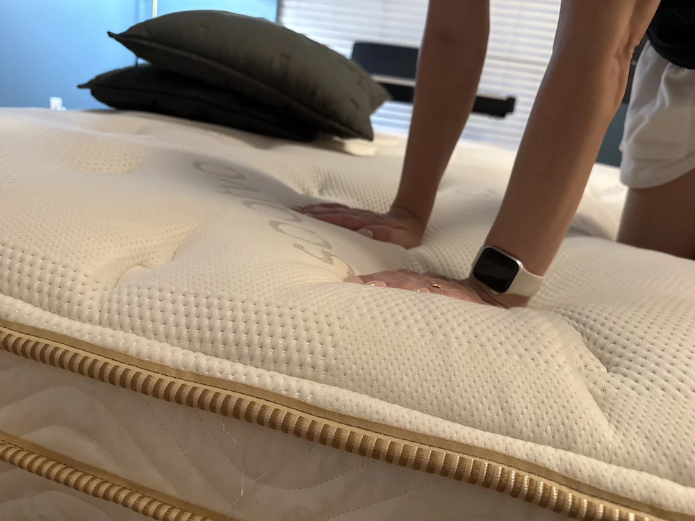 Pressing into Saatva Classic Euro pillow top to test contouring