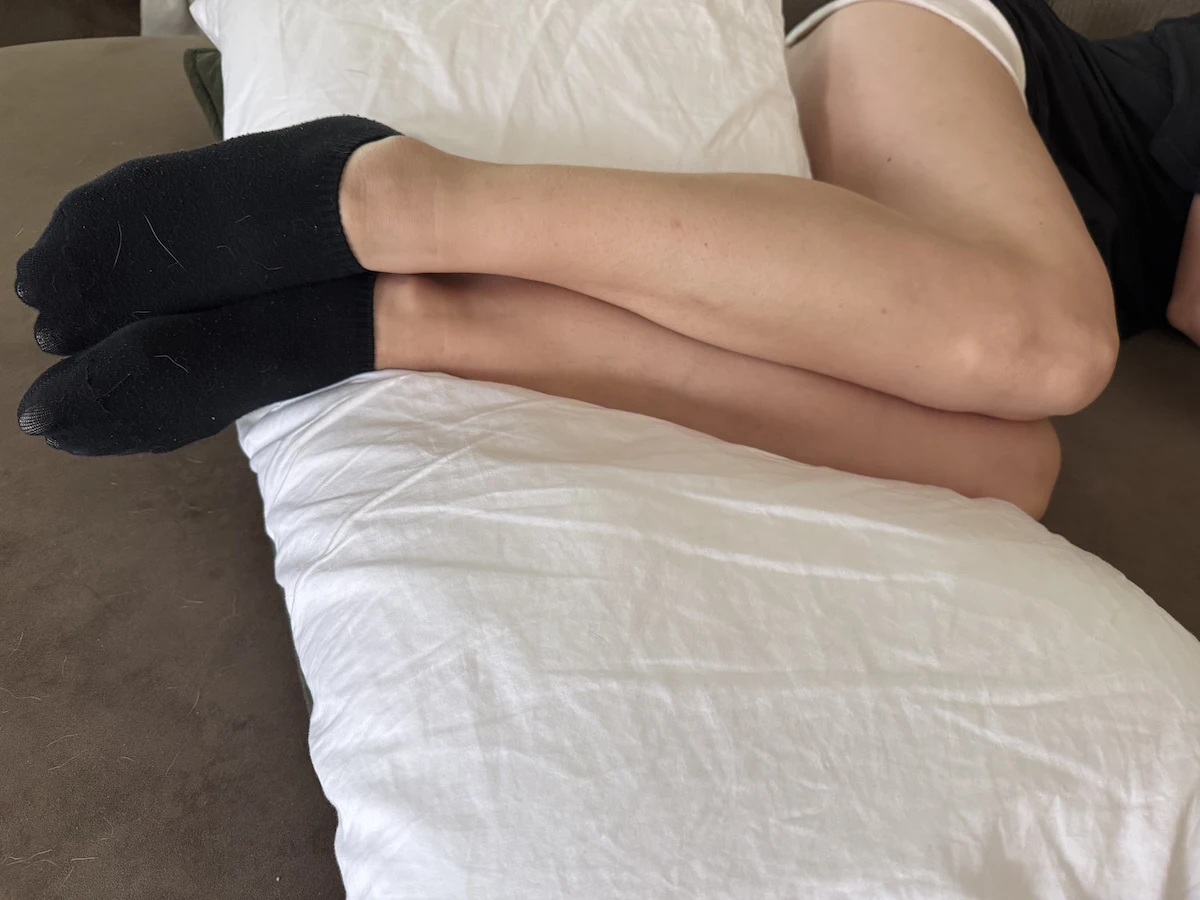 Close-up of legs supported by a pillow during side sleeping for comfort and circulation