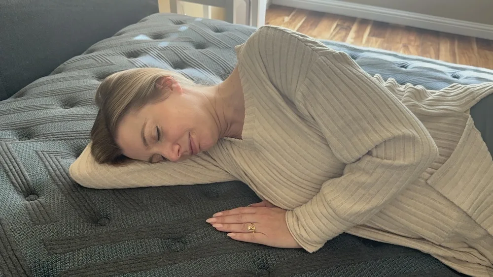 Side sleeper lying on mattress demonstrating pressure relief at shoulders and hips