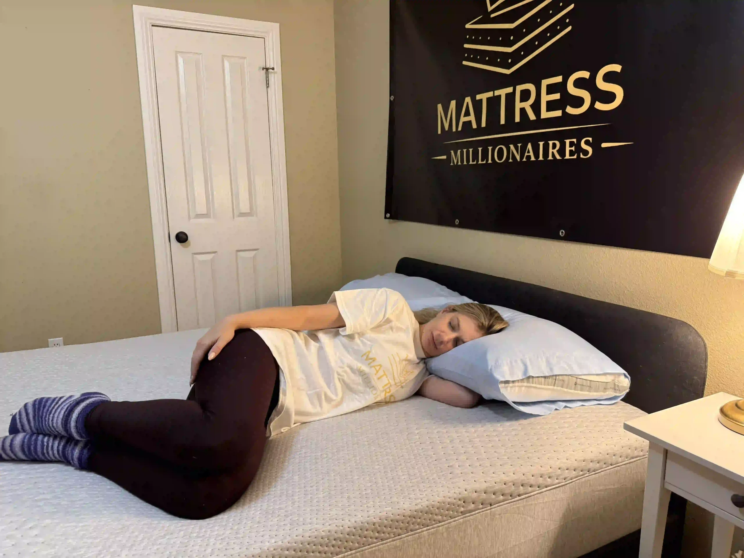 Woman demonstrating proper side sleeping posture with head supported by pillow on a mattress