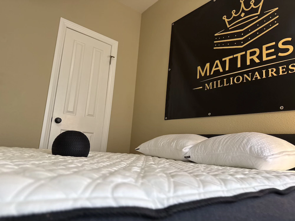Black textured ball resting in a shallow indentation on a white quilted mattress