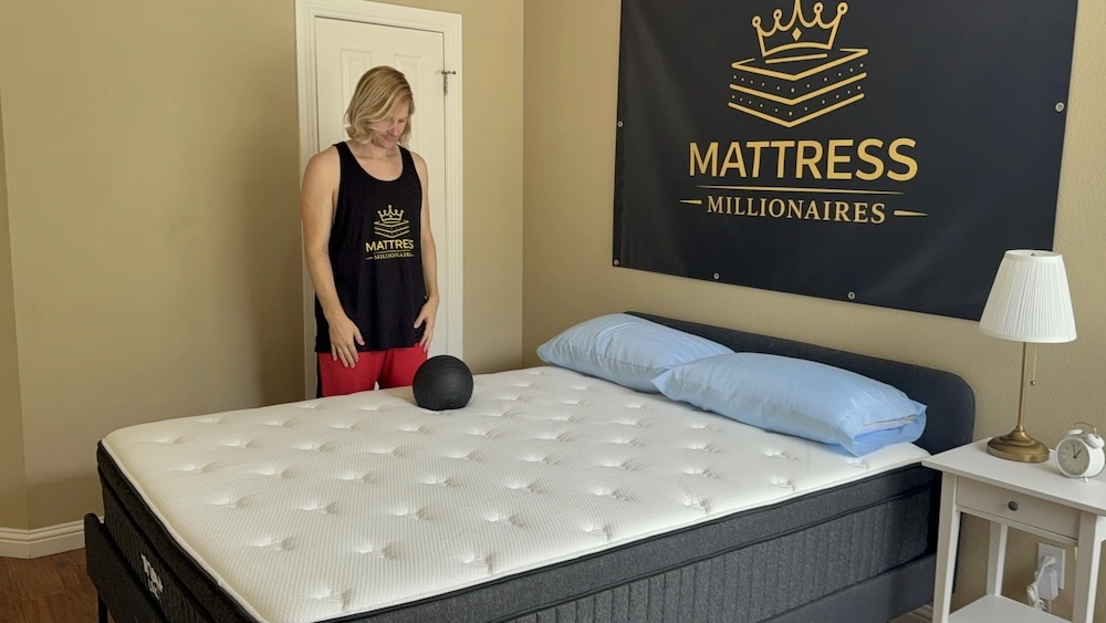 Tester standing beside the Titan Plus Luxe with a black testing ball on the mattress surface.